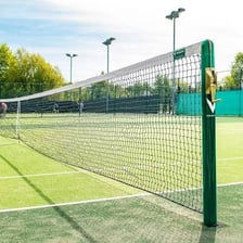 A tennis court with a net and painted boundary lines