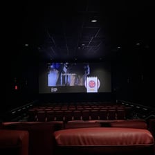 A movie theater viewed from the rear, with a projector behind the back row.