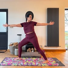 A yoga instructor standing on a mat during a class.
