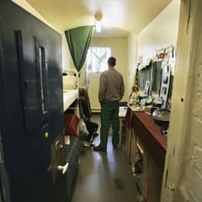 A person inside a prison cell behind bars.