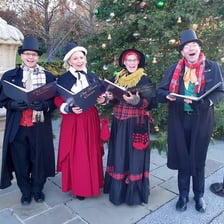 A group of carolers singing seasonal songs outdoors.
