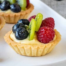 Several sweet fruit tarts on a serving tray