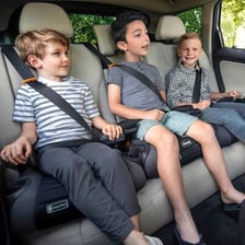 Children seated safely in booster seats inside a car.