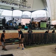 Concert road crew members setting up instruments and stage equipment