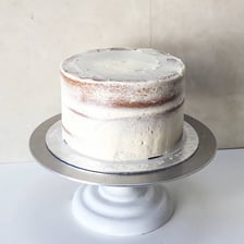 A cake being decorated with a layer of icing