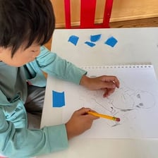 A hand using a pencil to trace over an existing outline.