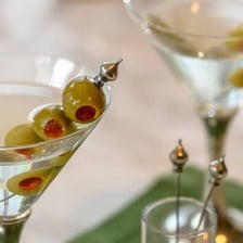 A martini garnished with a green olive on a cocktail pick.