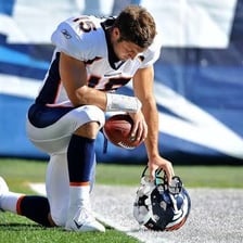 Tim Tebow kneeling with his head bowed in prayer