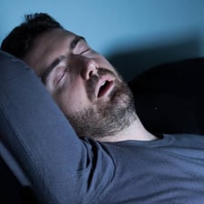 A sleeping person snoring in bed.