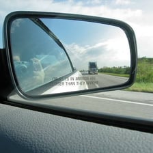 A car seen from the front with its two side mirrors projecting outward.