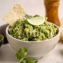 Lime wedges beside a bowl of guacamole