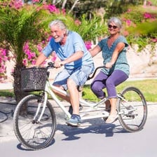 Two riders seated one behind the other on a tandem bicycle.