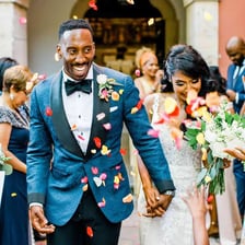Wedding guests tossing flower petals over a newly married couple.
