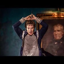 An actor making an exaggerated theatrical gesture on stage