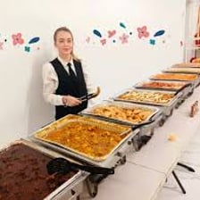Person serving a second helping from a buffet