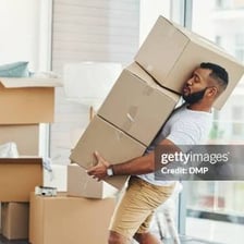 A person leaning forward and exerting effort while pushing a heavy object.