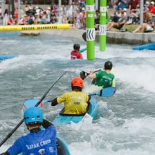 A canoeist navigating an Olympic-style slalom course through whitewater gates.