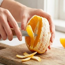 A cut orange with its white pith visible beneath the peel.