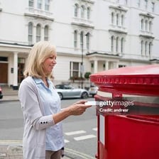 A person placing a letter into a mailbox.