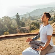 A person meditating peacefully outdoors.