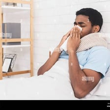 A person with cold symptoms holding a tissue.