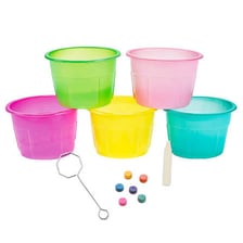 Cups of colored dye beside eggs being decorated