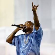 A rapper performing into a microphone on stage.