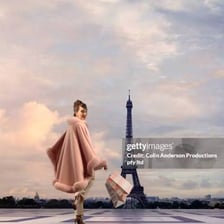 A woman walking in a Parisian setting near the Eiffel Tower.