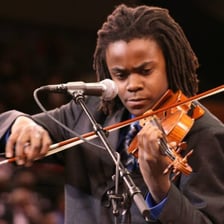 A violinist bows the strings of a violin.