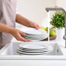A person washing dishes at a kitchen sink.