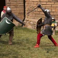 Two people facing each other with swords in a historical duel reenactment.