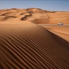 A large sand dune with rippled slopes in a desert.