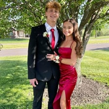 Teenagers dressed in formalwear pose together at a school prom.