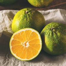 A wrinkled Ugli citrus fruit shown whole and cut open.