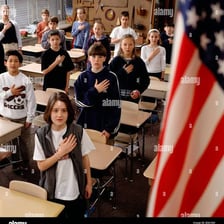 Children standing beside an American flag during a pledge.