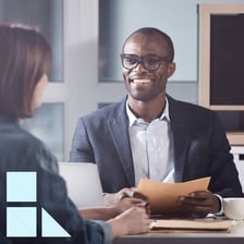 A job interviewer speaking with a candidate across a desk.