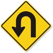 A road sign or roadway scene showing a car making a U-turn.