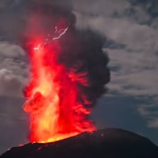 An erupting volcano releasing smoke and lava.