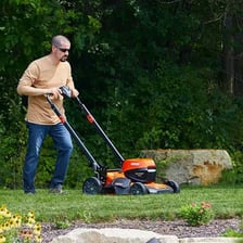 A person mowing a grassy residential lawn