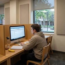Students sit at computers in a quiet testing room.