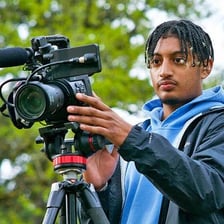 A documentary filmmaker recording nonfiction footage with a camera.