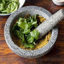 Fresh pesto being ground in a mortar with a pestle
