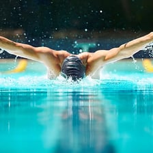 A swimmer performing the butterfly stroke in a pool.