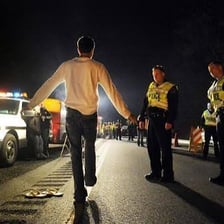 A police officer conducts a nighttime traffic stop.