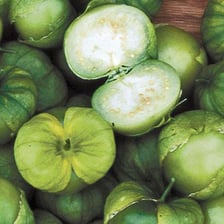 A green tomatillo partly enclosed in its papery husk.