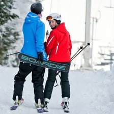 A snowboarder being pulled uphill by a T-bar lift