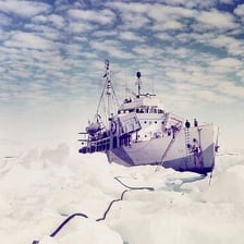 An icebreaker ship moving through broken sea ice.