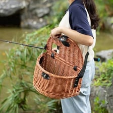 A traditional woven fishing creel basket beside a stream.