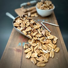 A pecan nut shown in its shell and as an edible kernel.