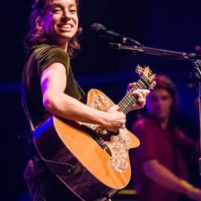 Ani DiFranco performing onstage with a guitar.